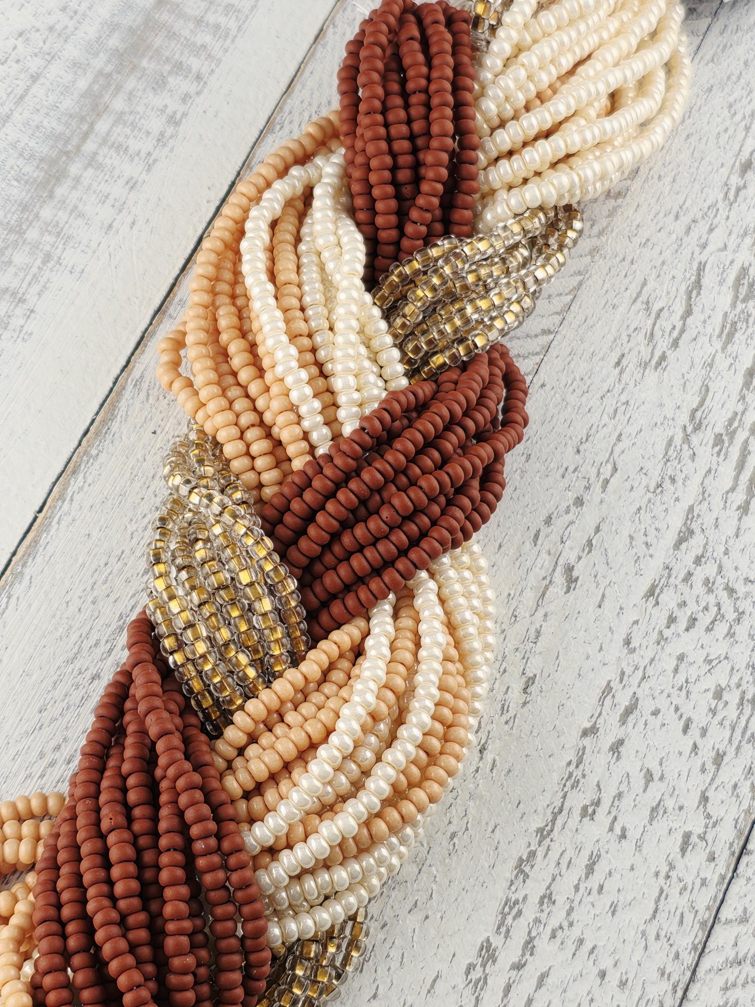 A collection of colorful beads, including white, brown, and beige beads, arranged in a braided pattern on a wooden surface.