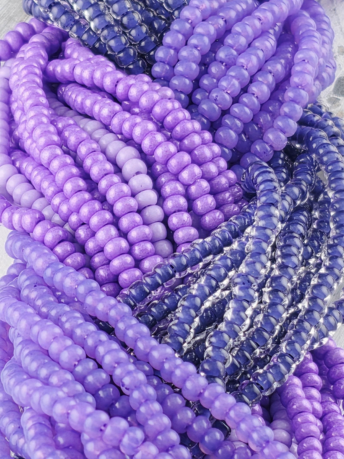 A close-up image of a collection of colorful beads, predominantly purple and blue, arranged in a visually appealing manner.