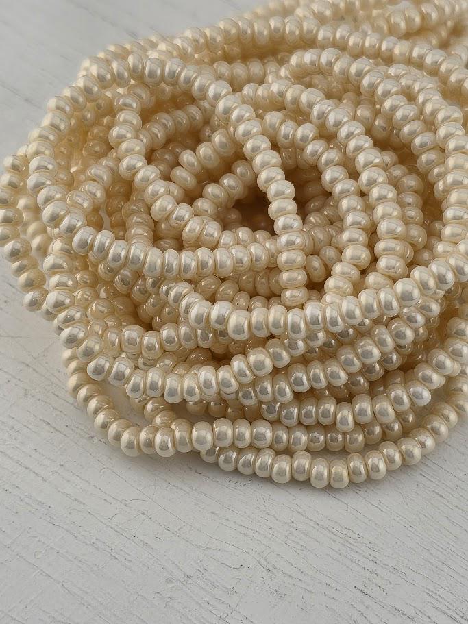 A close-up image of numerous white, round beads arranged in a circular pattern on a white surface.