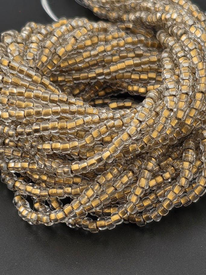 a close-up view of a pile of clear glass beads with a gold-colored center, arranged in a circular pattern.