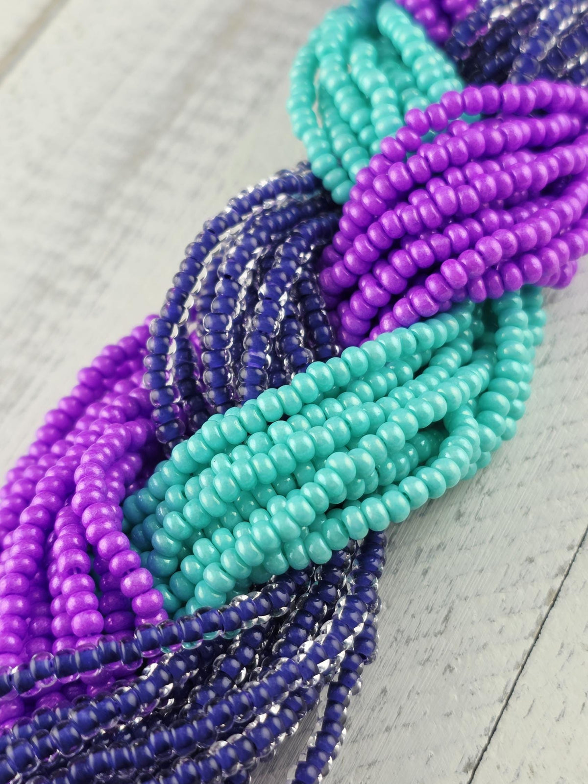 A close-up view of a collection of colorful beads, including purple, blue, and turquoise beads, arranged in a tangled or braided manner.
