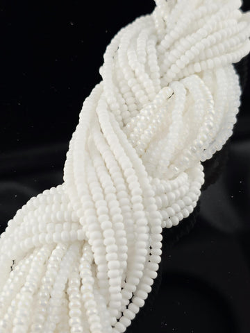 A close-up view of numerous white beads arranged in a twisted, braided pattern against a dark background.