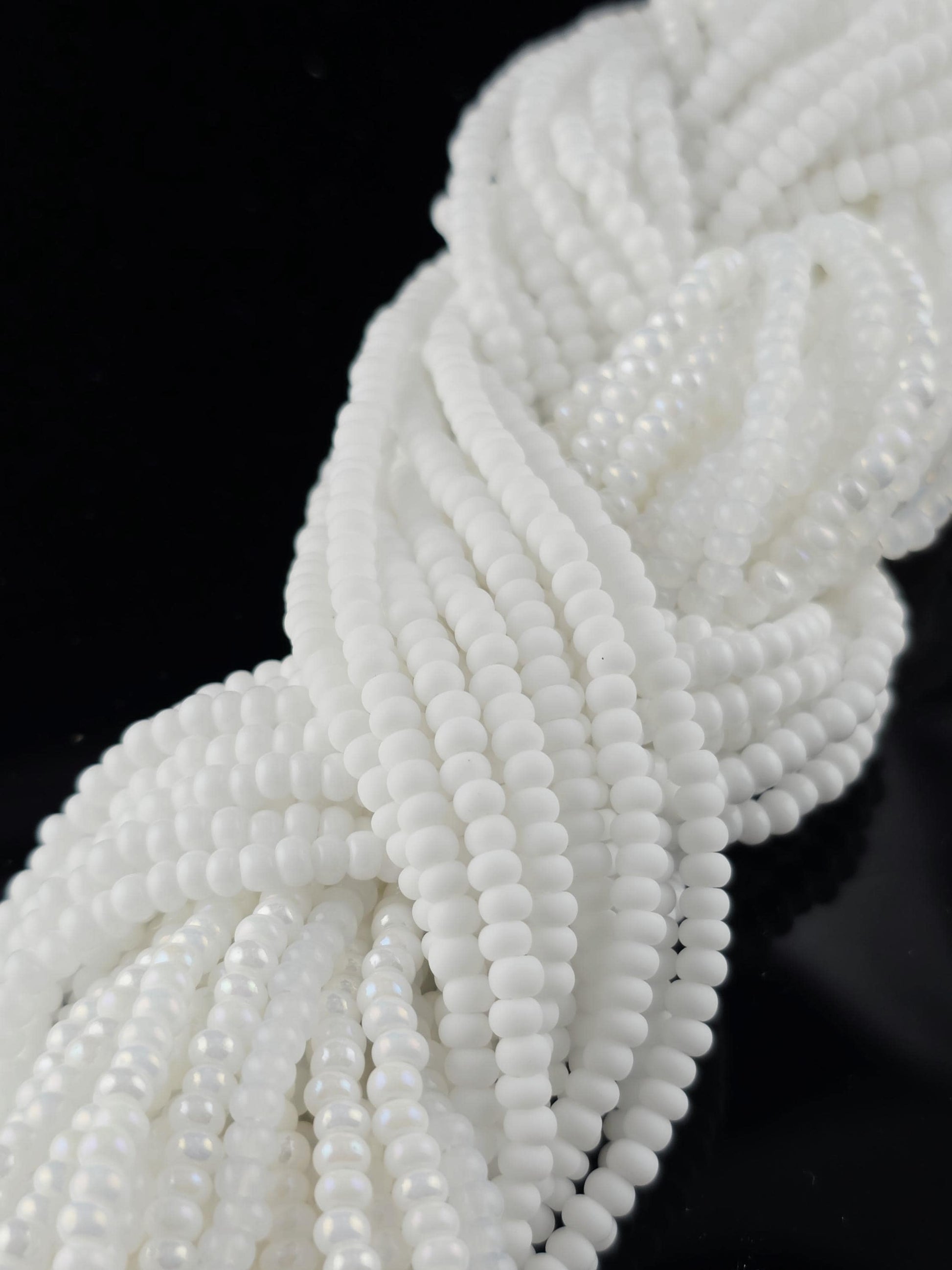 A close-up view of numerous white beads arranged in a twisted or braided pattern against a black background.