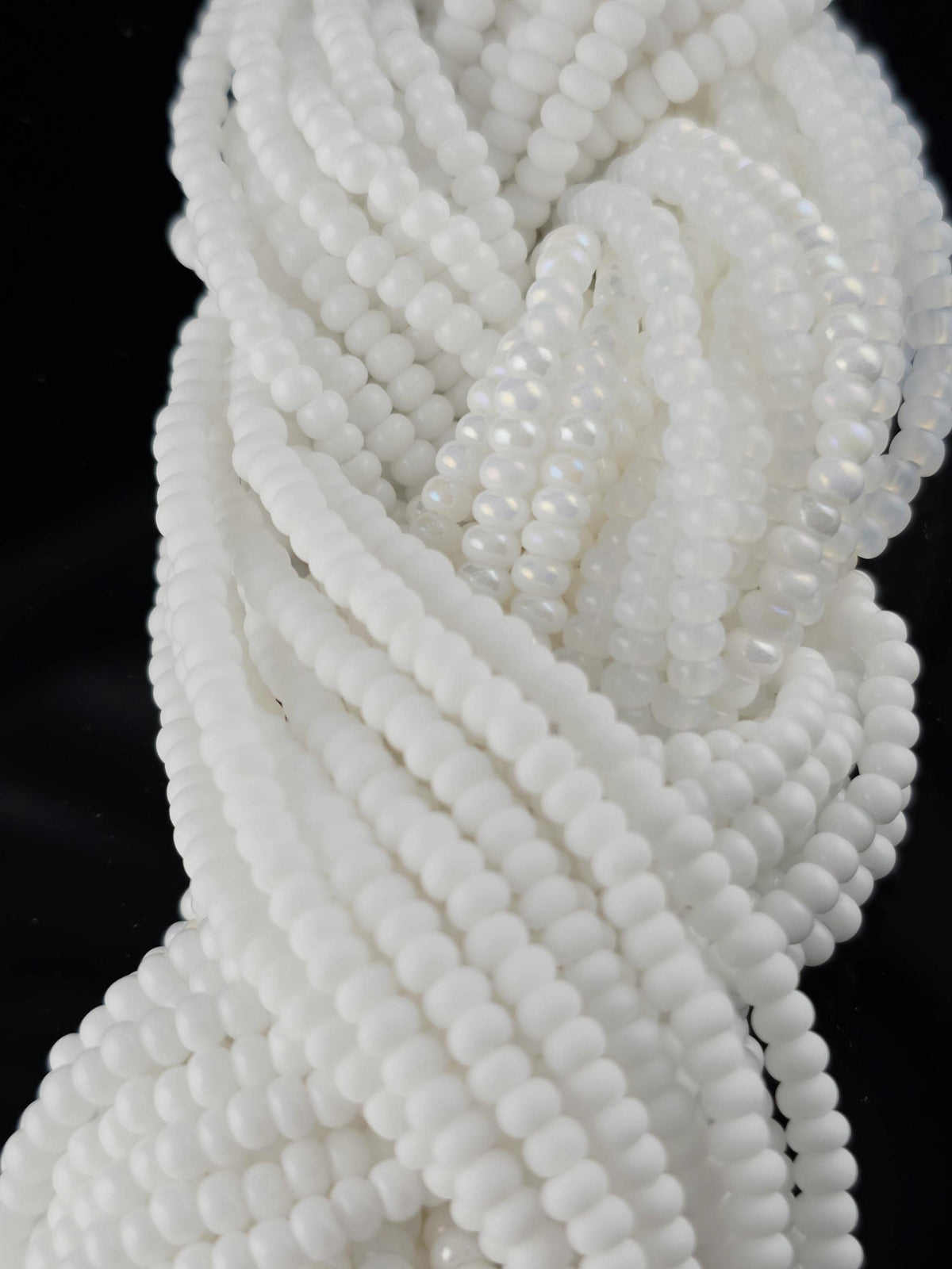 A close-up image of numerous white beads arranged in a spiral pattern against a black background.