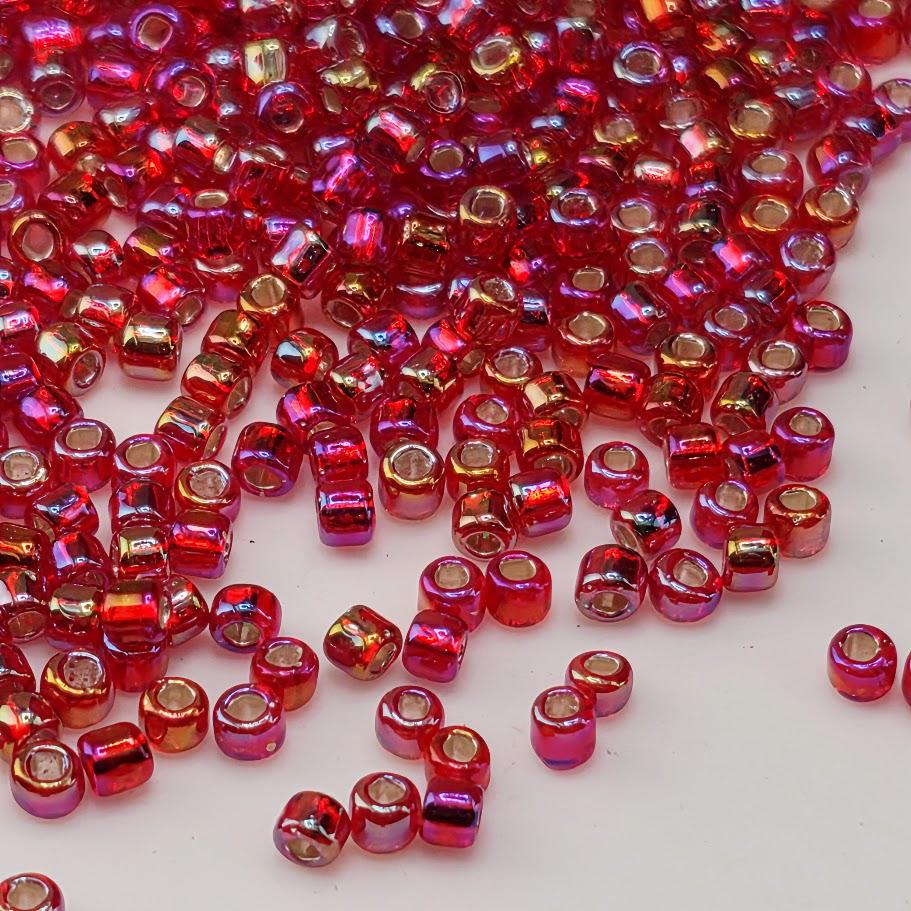a large pile of red and gold beads scattered on a white surface.