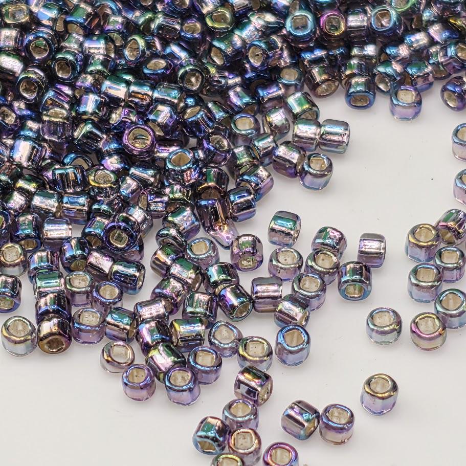 a collection of multicolored beads, including purple, blue, and green, scattered across a white surface.