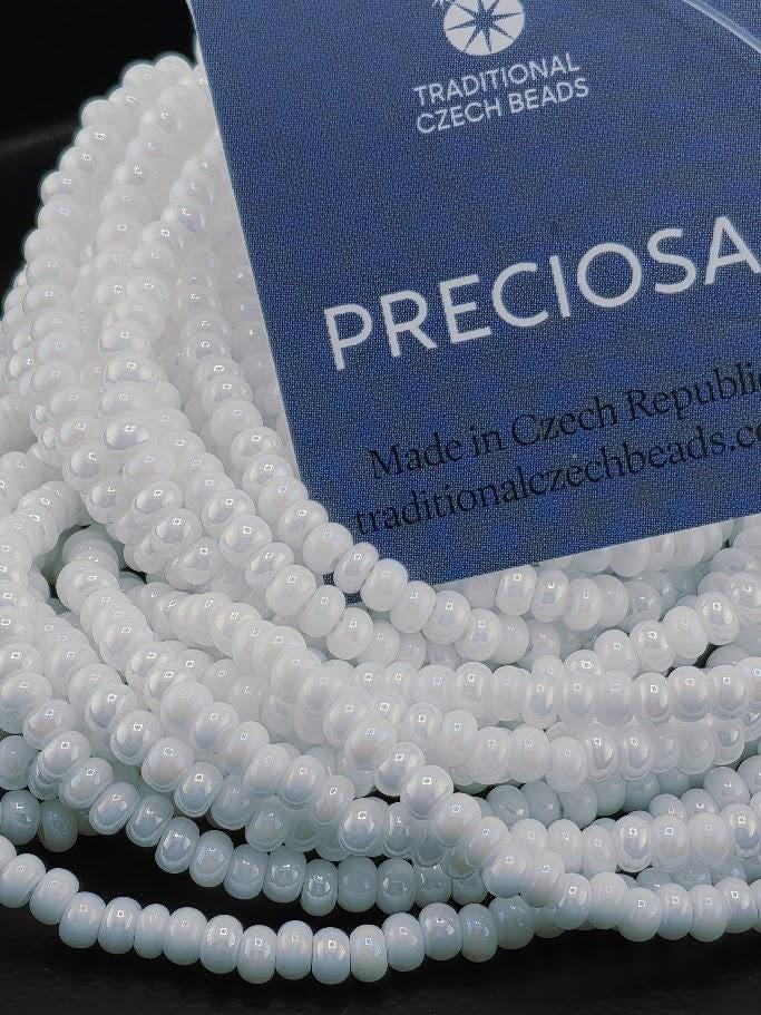 A pile of white beads, possibly made of glass or plastic, is displayed next to a blue tag with text.