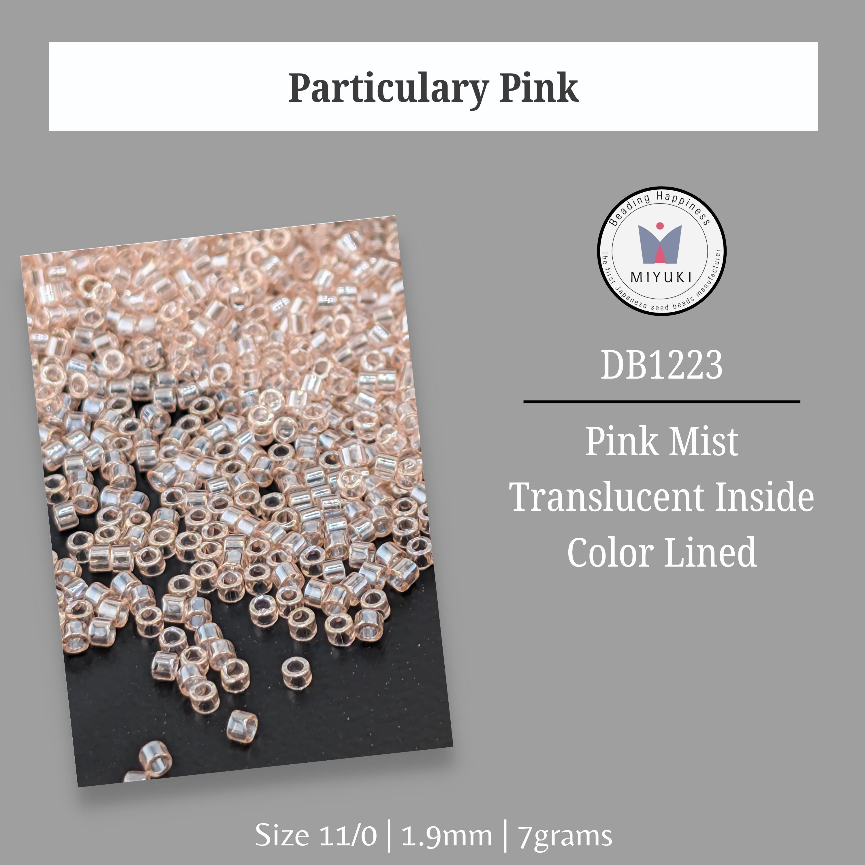 a collection of small, clear beads in various colors, including pink and white, scattered on a black background.
