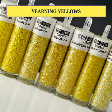 A collection of glass containers filled with yellow beads, each labeled with a different color.