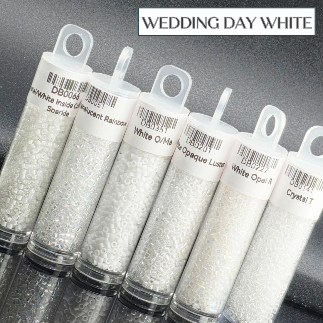 A collection of six clear plastic containers filled with white beads, each labeled with a different color.