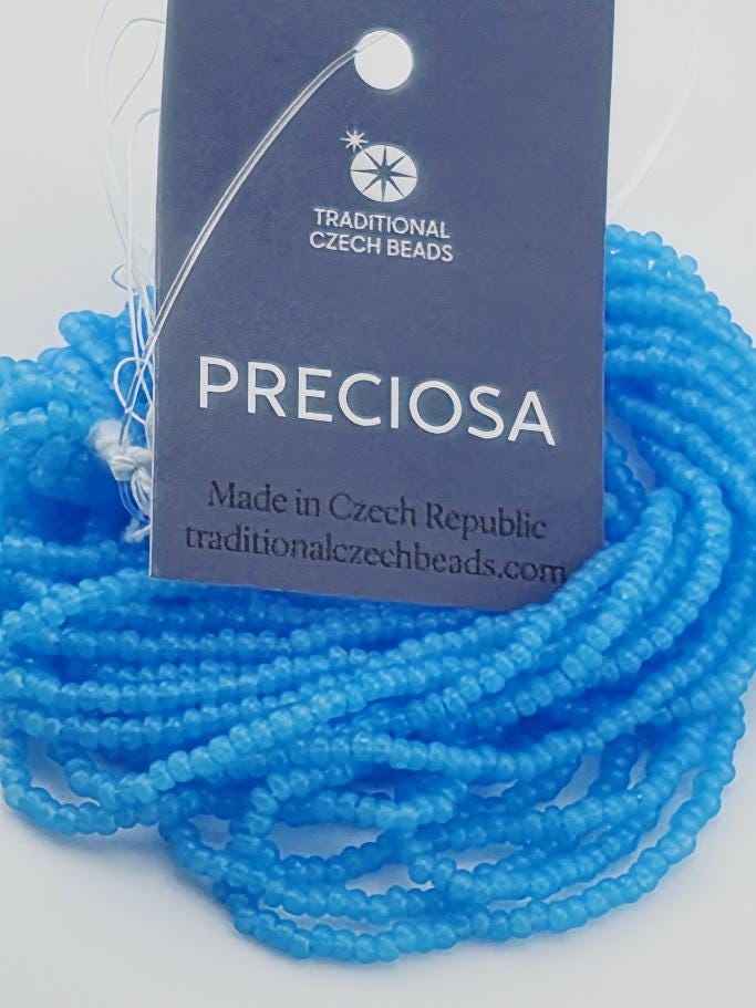 a close-up view of a blue bead necklace with a tag that reads "PRECIOSA" and "Made in Czech Republic".
