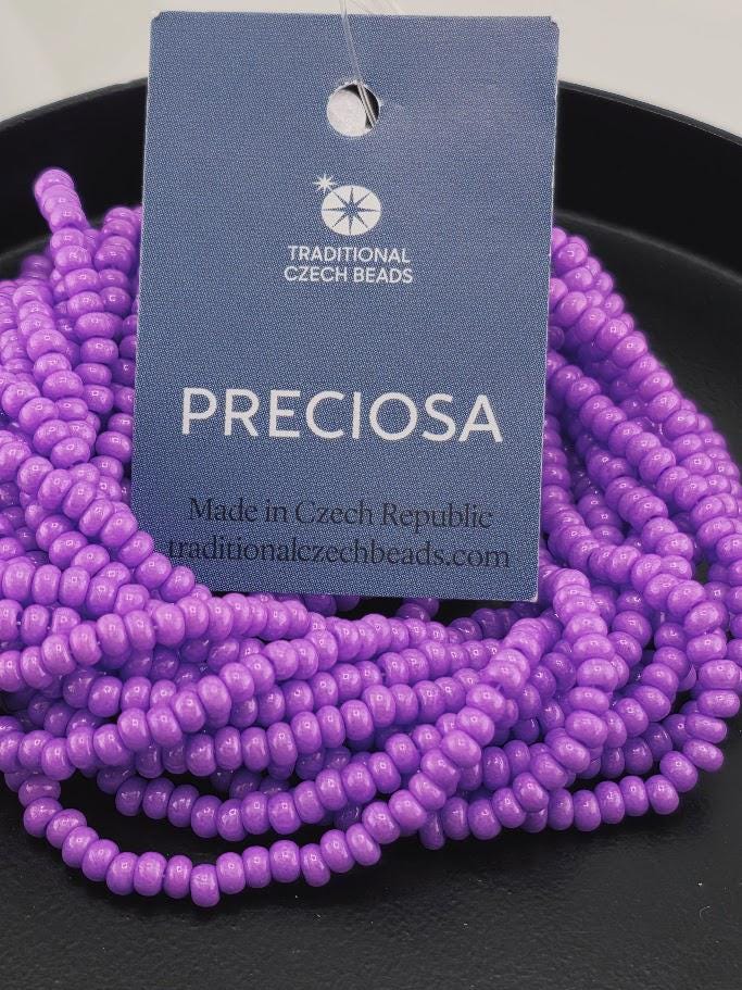 a collection of purple beads arranged on a black surface, with a tag attached to one of the beads.