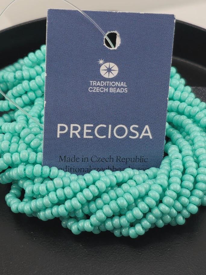 A close-up image of a blue tag with text and a logo, surrounded by turquoise beads on a black surface.