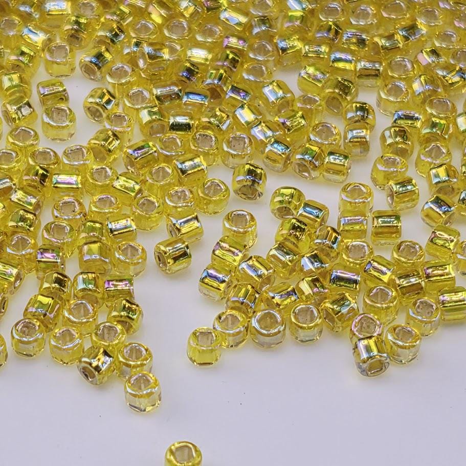 a collection of small, yellow glass beads scattered across a white background.