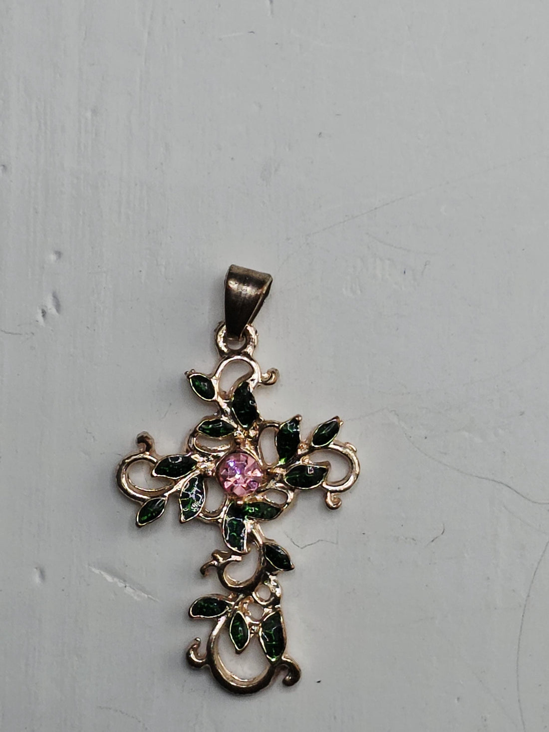 a decorative pendant with a floral design and a pink gemstone, placed within an ornate, silver-colored frame.