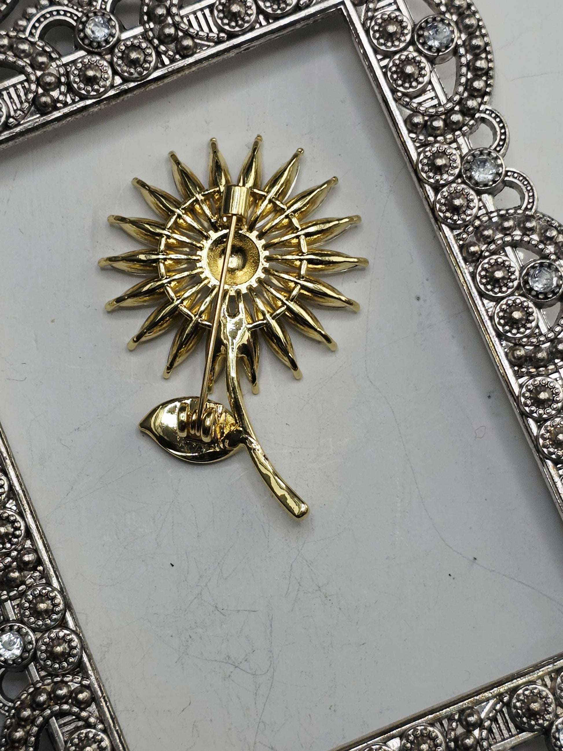 a decorative frame with a gold-colored sun-shaped brooch or pendant attached to it.