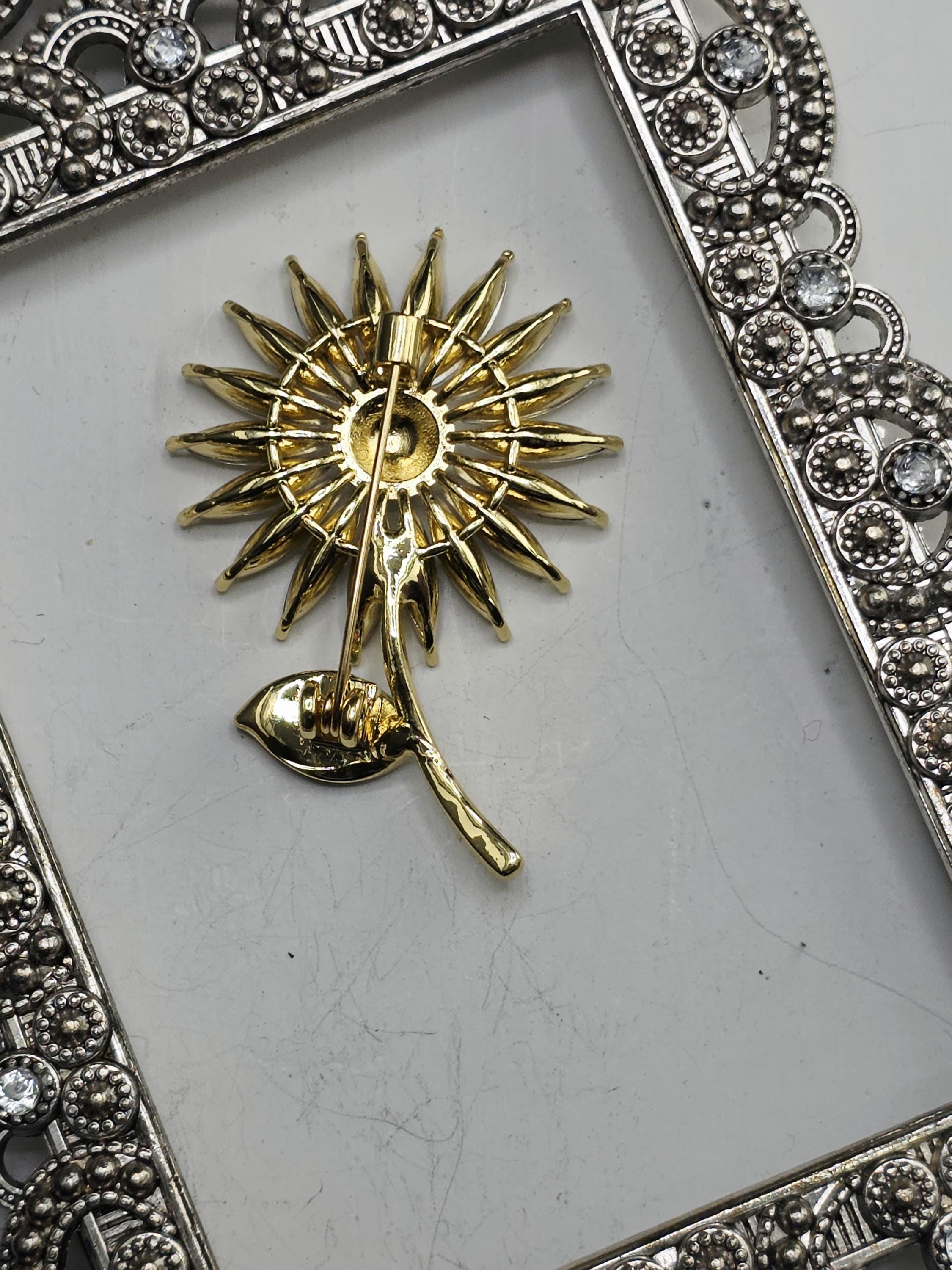 a decorative frame with a gold-colored sun-shaped brooch or pendant attached to it.