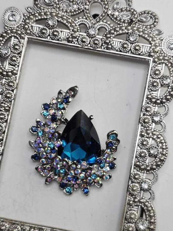 a large, blue gemstone set in an ornate, silver-colored frame.