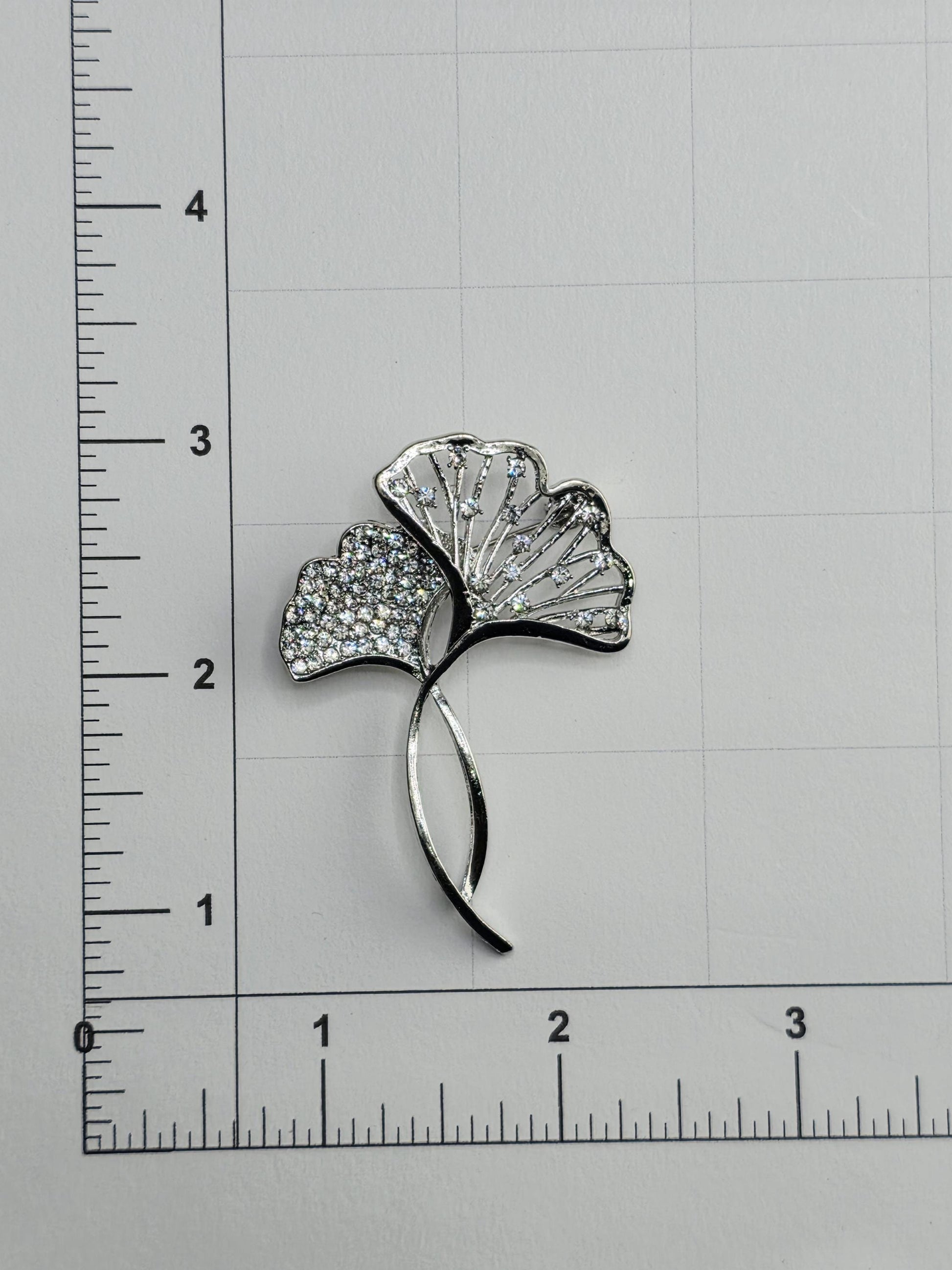 A close-up image of a decorative piece with a leaf-like design, featuring small diamonds or crystals embedded in it.