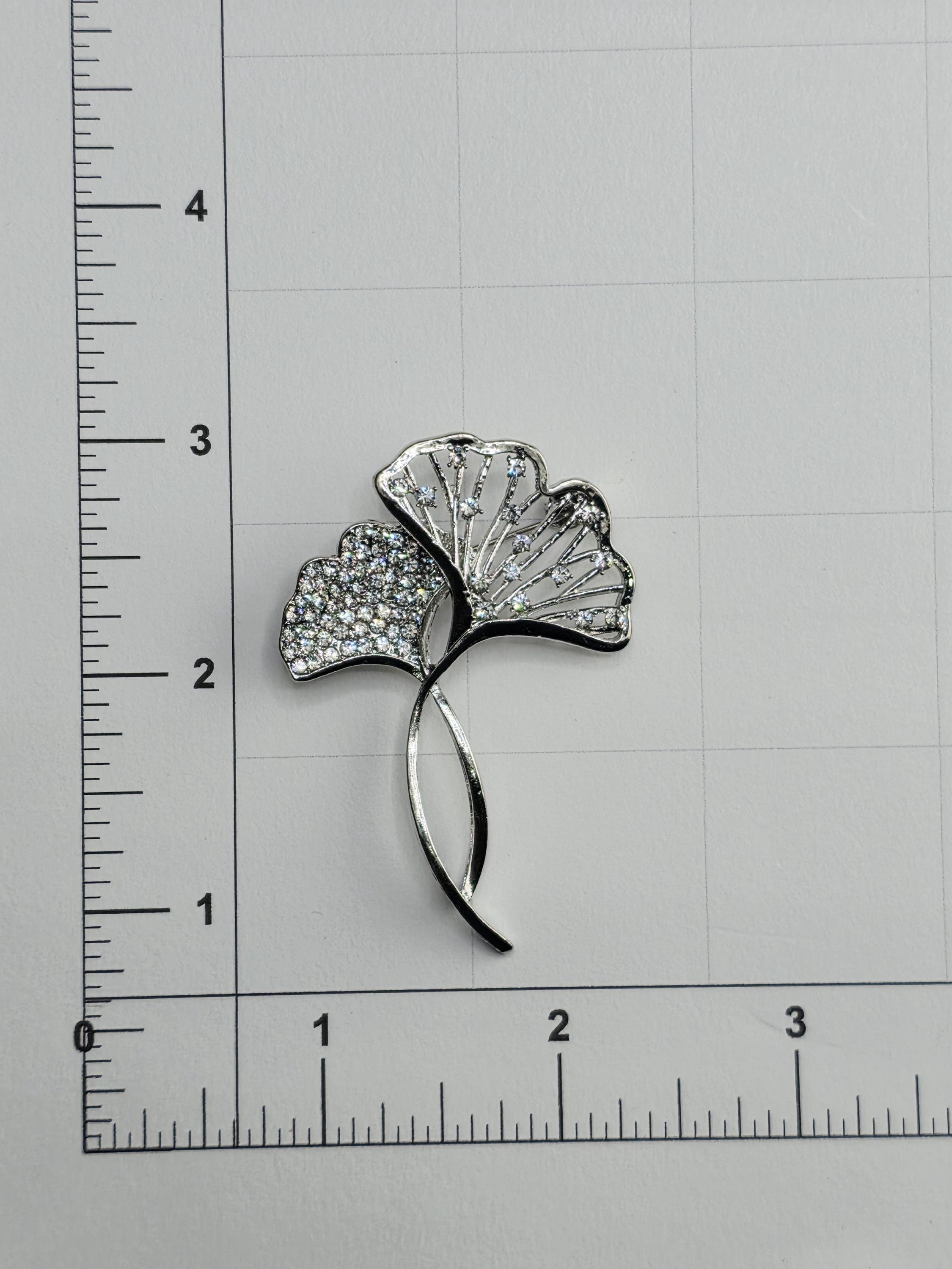 A close-up image of a decorative piece with a leaf-like design, featuring small diamonds or crystals embedded in it.