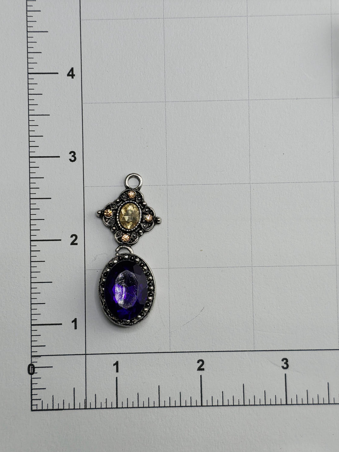 a silver ornate frame with a large purple gemstone hanging from it.