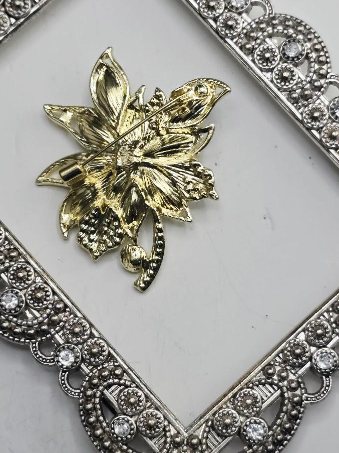 a decorative piece of jewelry, possibly a brooch or pendant, with a floral design and a metallic frame.