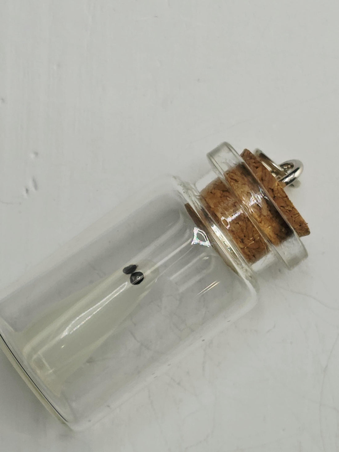A clear glass bottle with a cork stopper is placed inside a decorative silver frame with intricate designs.