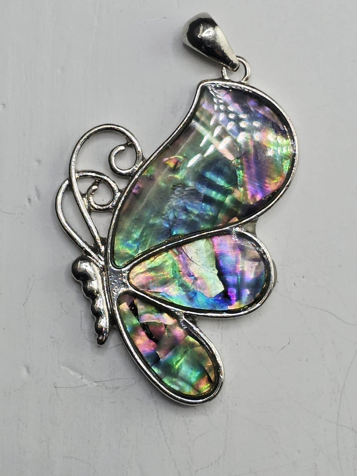 A silver butterfly pendant with a colorful iridescent pattern on its wings.