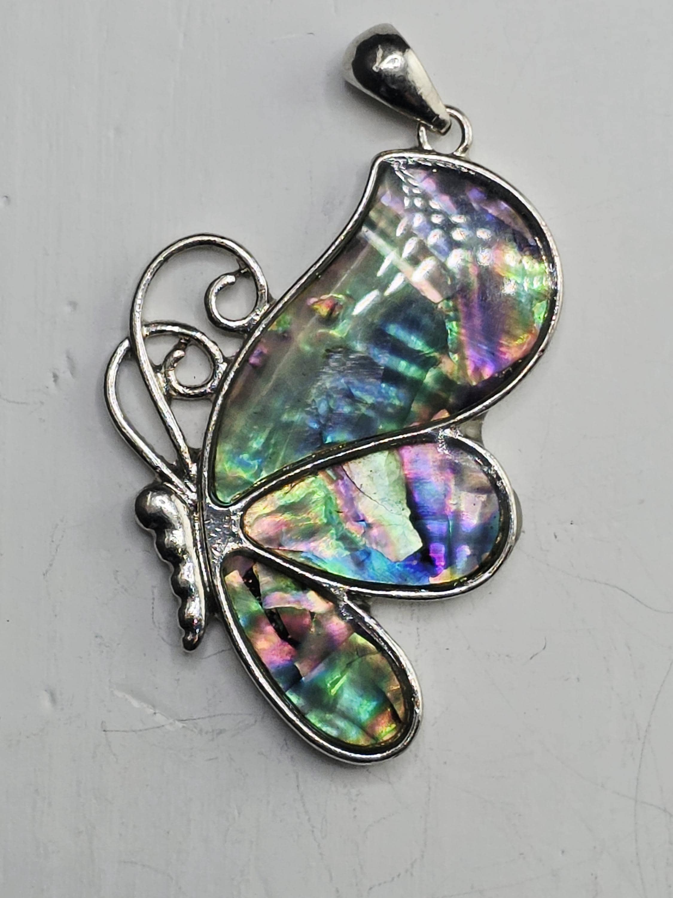 A silver butterfly pendant with a colorful iridescent pattern on its wings.