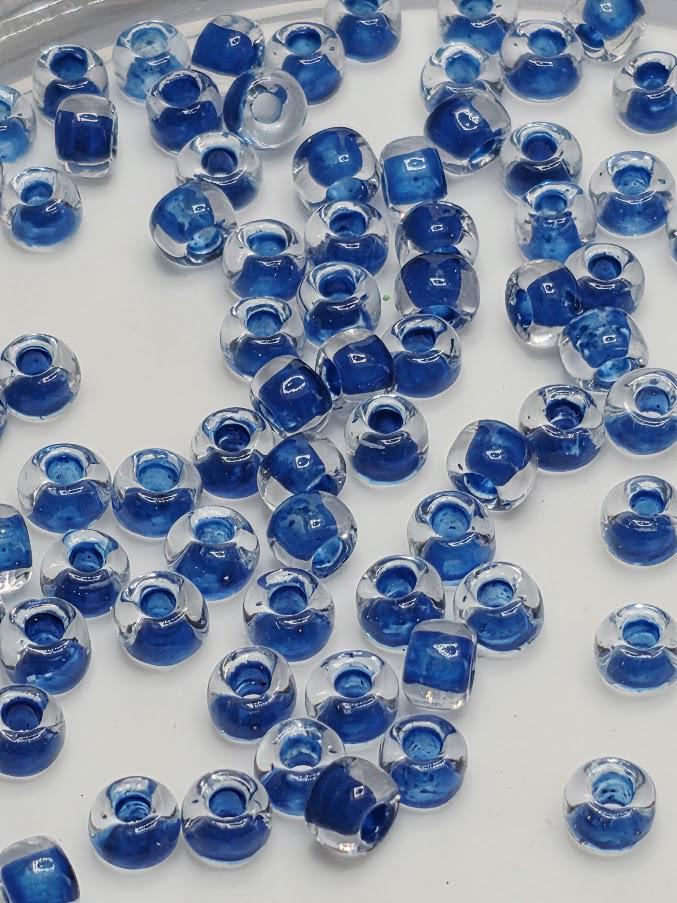 a collection of clear glass beads in various shades of blue, scattered across a white background.