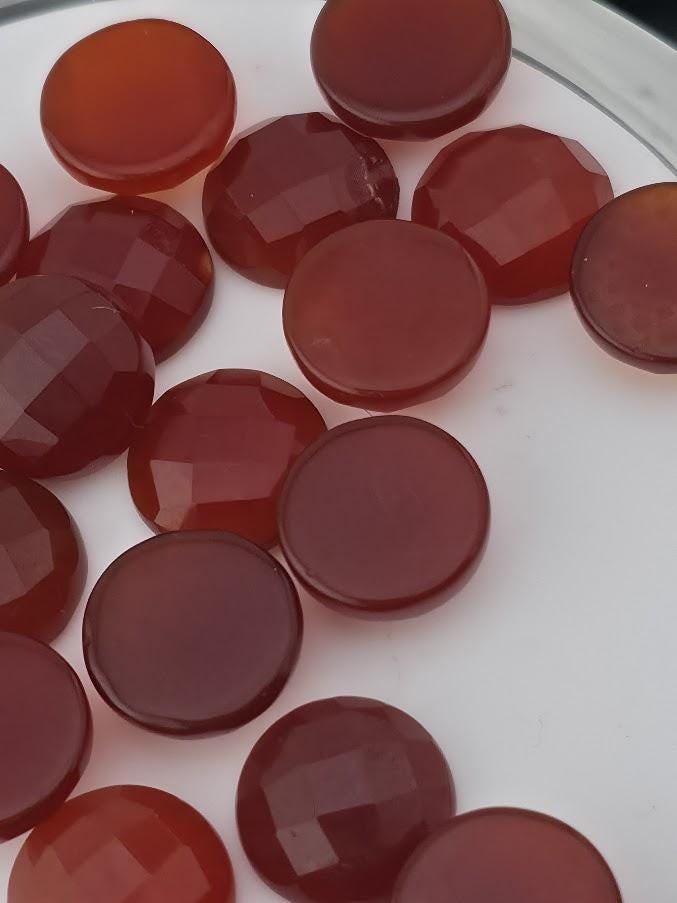 a collection of red and orange gemstones or stones arranged on a white surface.