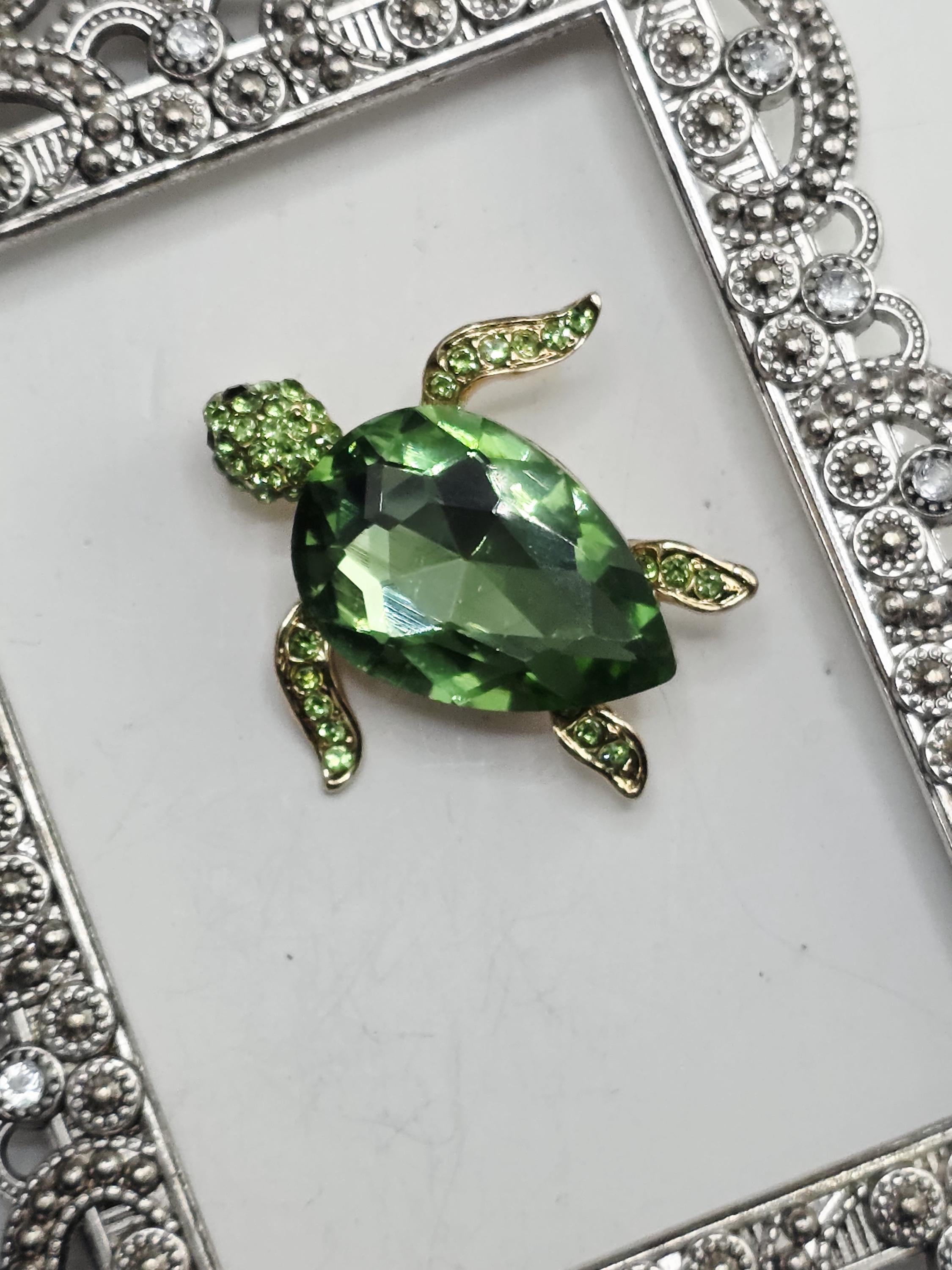 A decorative frame with a large green gemstone in the center, surrounded by smaller green gemstones.