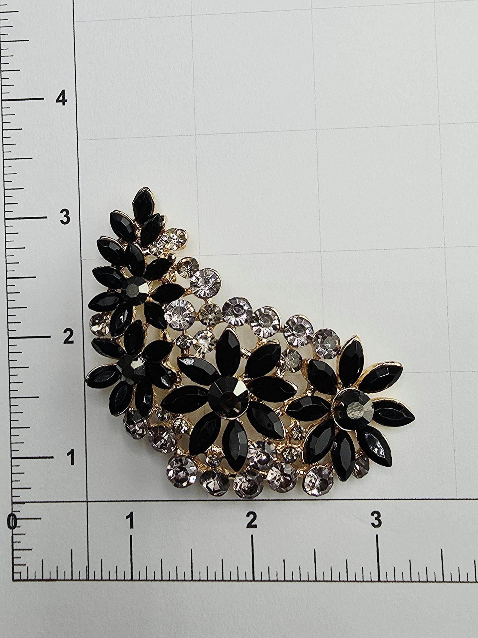 a close-up view of a decorative piece with black and gold elements, including a floral design and small crystals.