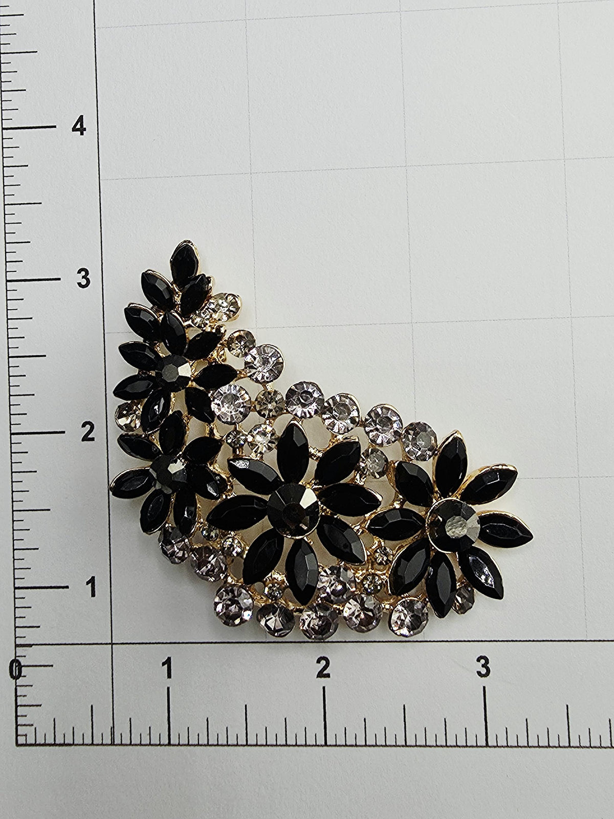 a close-up view of a decorative piece with black and gold elements, including a floral design and small crystals.