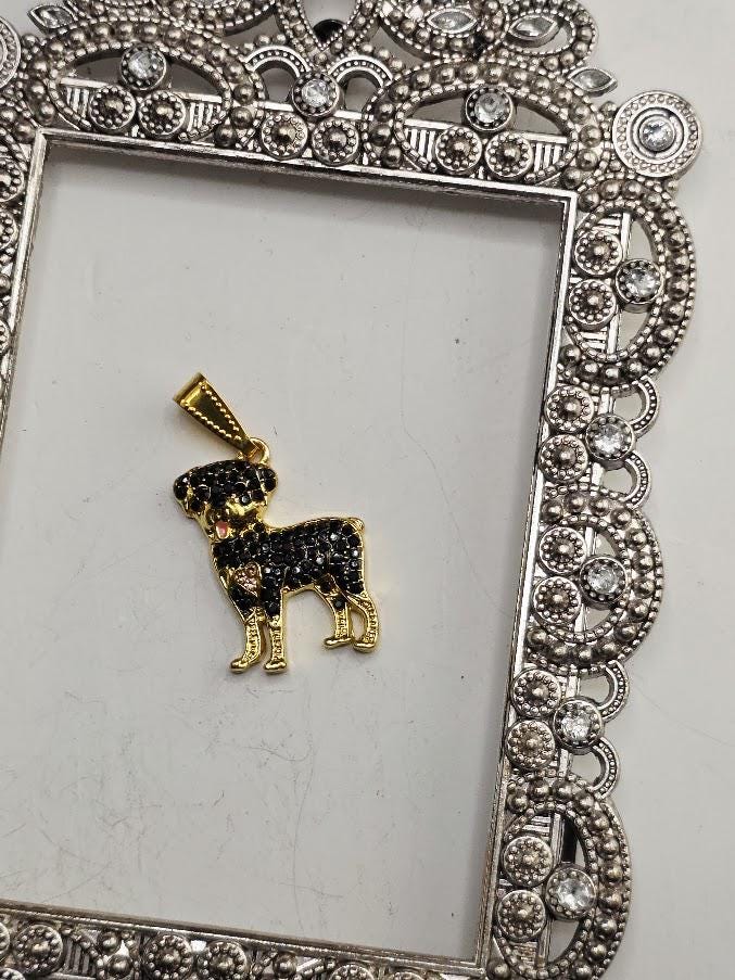 A gold-colored pendant in the shape of a dog is displayed in a decorative silver frame.