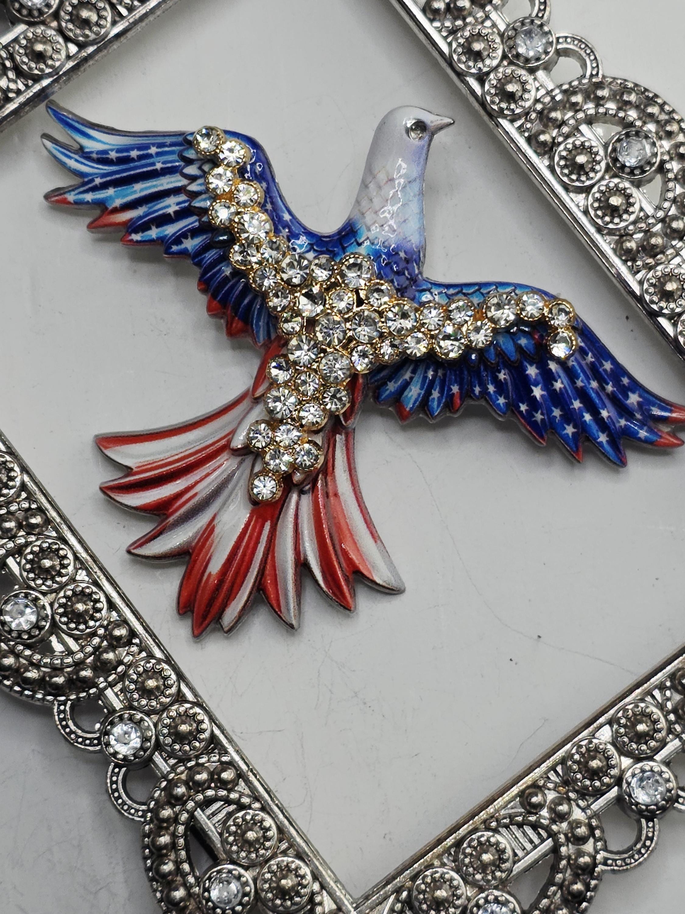 A decorative eagle brooch with a blue and red color scheme, adorned with numerous sparkling rhinestones.