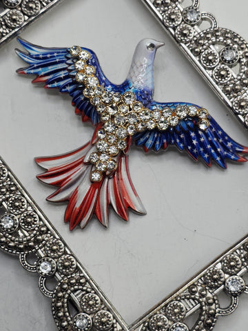 A decorative eagle brooch with a blue and red color scheme, adorned with numerous sparkling rhinestones.