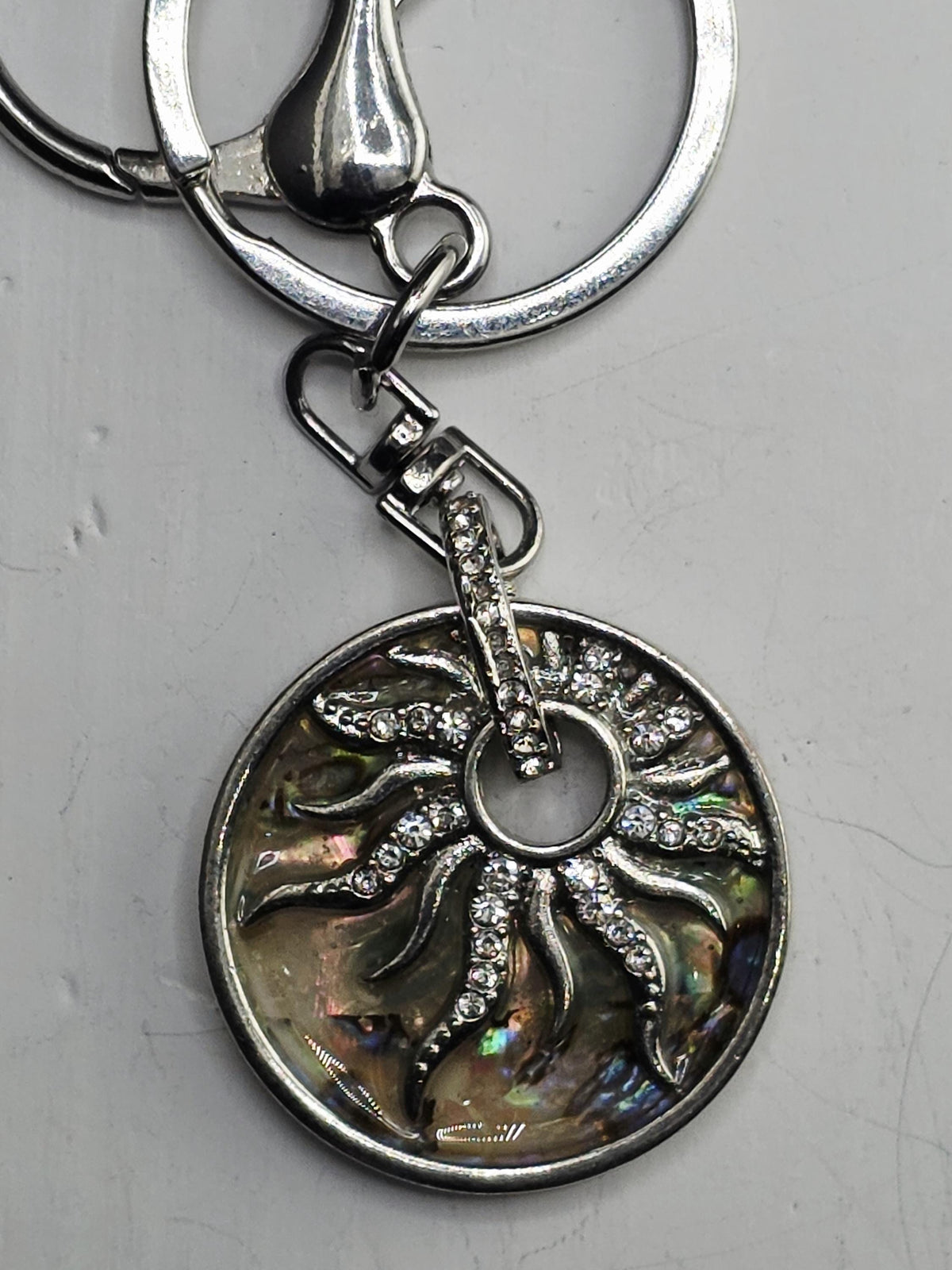 A silver keychain with a decorative sun-shaped pendant featuring sparkling crystals.