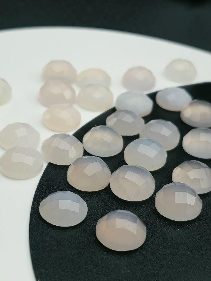a collection of small, white, and beige stones or gemstones arranged on a black surface.