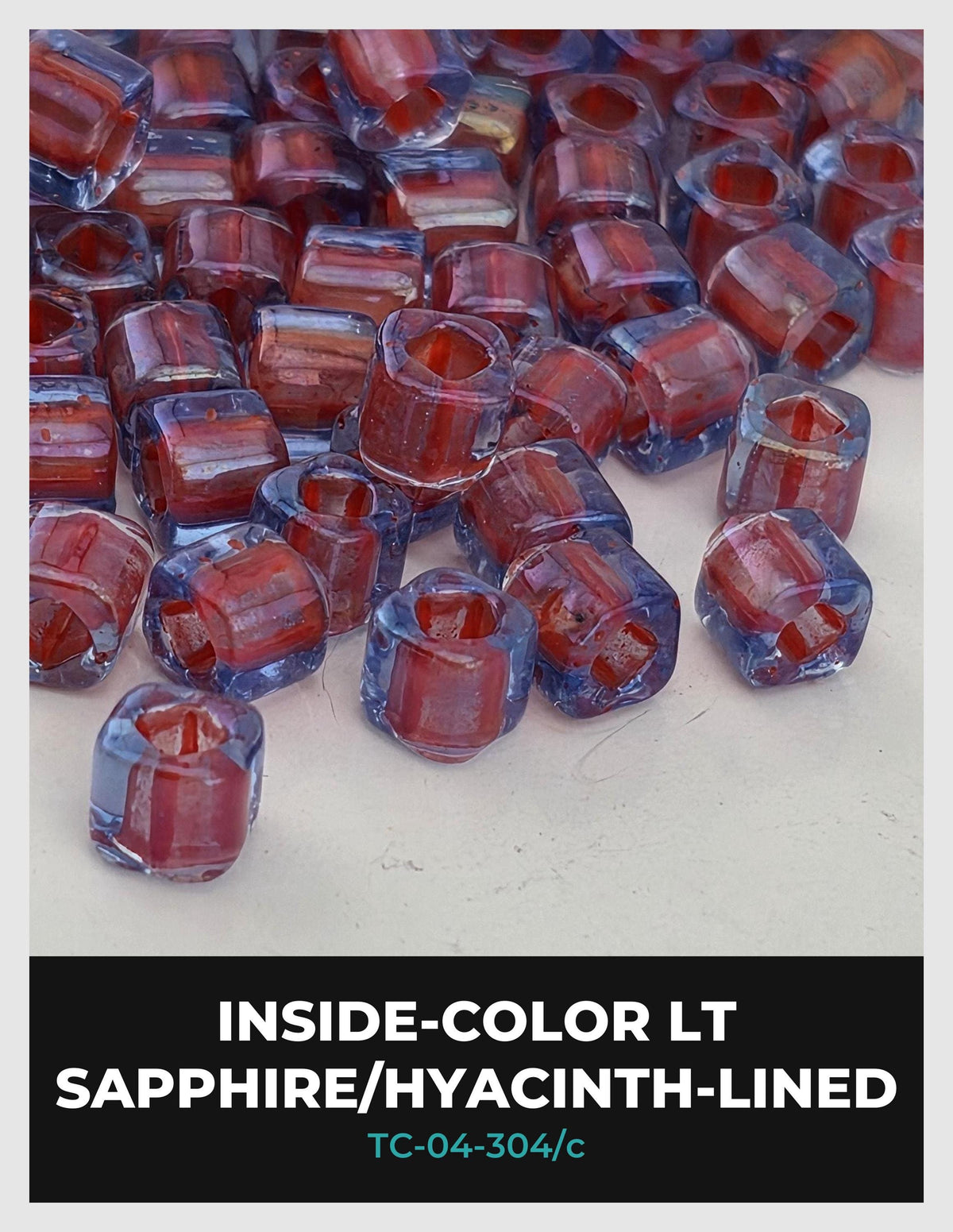a collection of clear glass beads in various colors, including red, blue, and purple, scattered on a white surface.