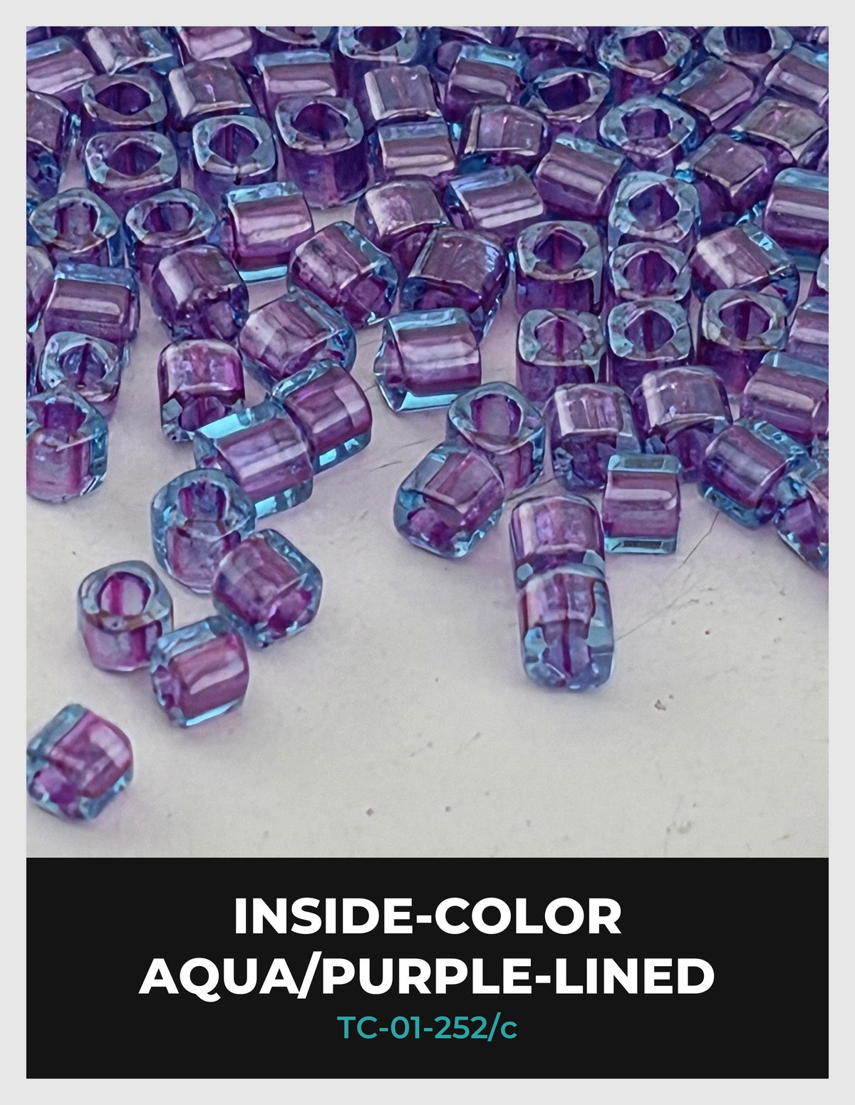 a collection of small, clear beads in various shades of purple and blue, scattered across a white surface.