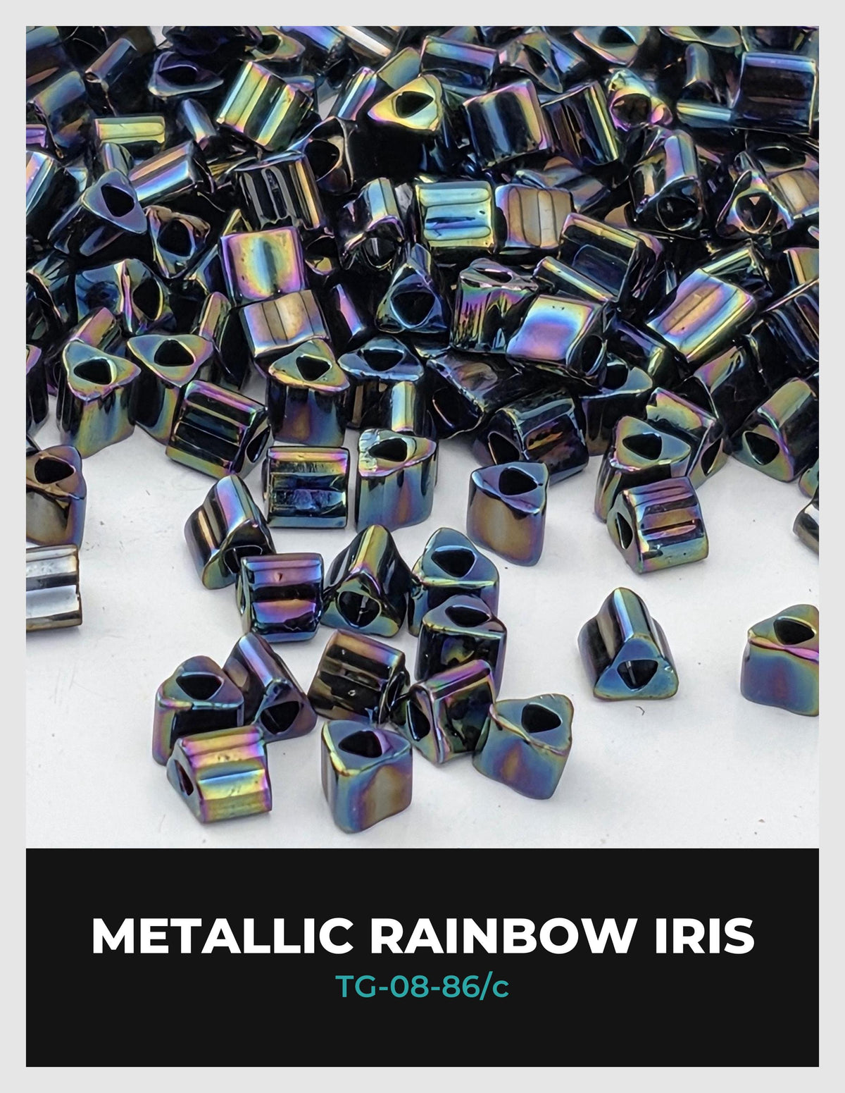 The image is a close-up of numerous metallic rainbow iris beads scattered on a white surface.