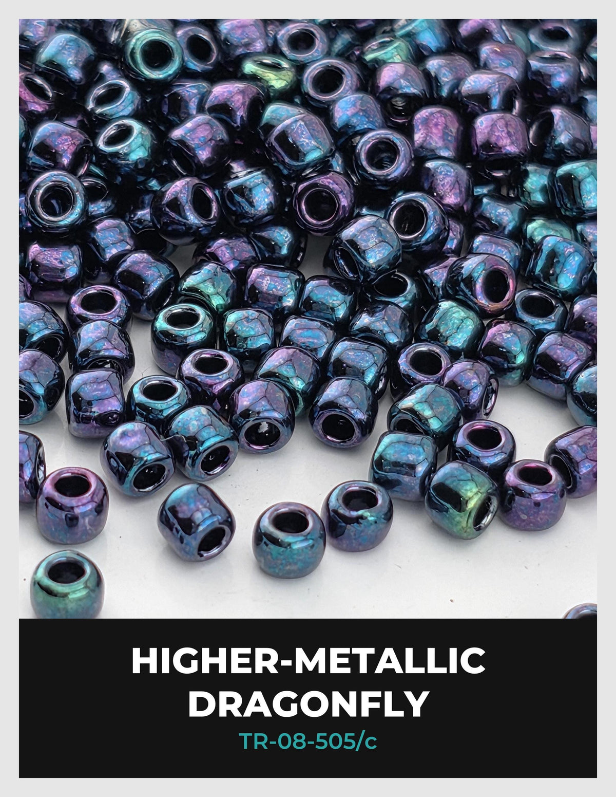 The image is a close-up of numerous metallic beads in various shades of blue and purple, scattered across a surface.