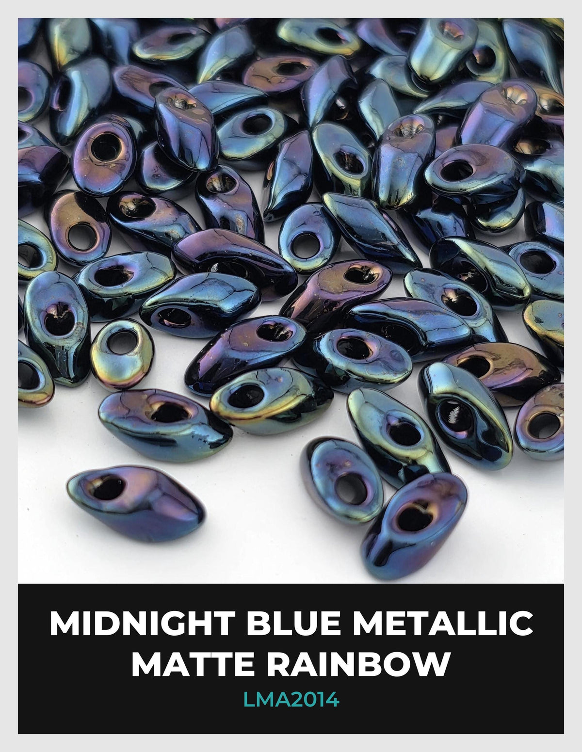 The image is a close-up of numerous metallic beads in various shades of blue, including metallic blue, metallic silver, and metallic green. The beads are scattered across a white background, creating a visually striking contrast.