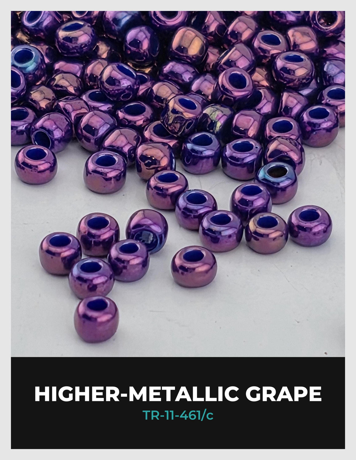 a collection of purple metallic beads, likely made of a shiny material, scattered on a white surface.