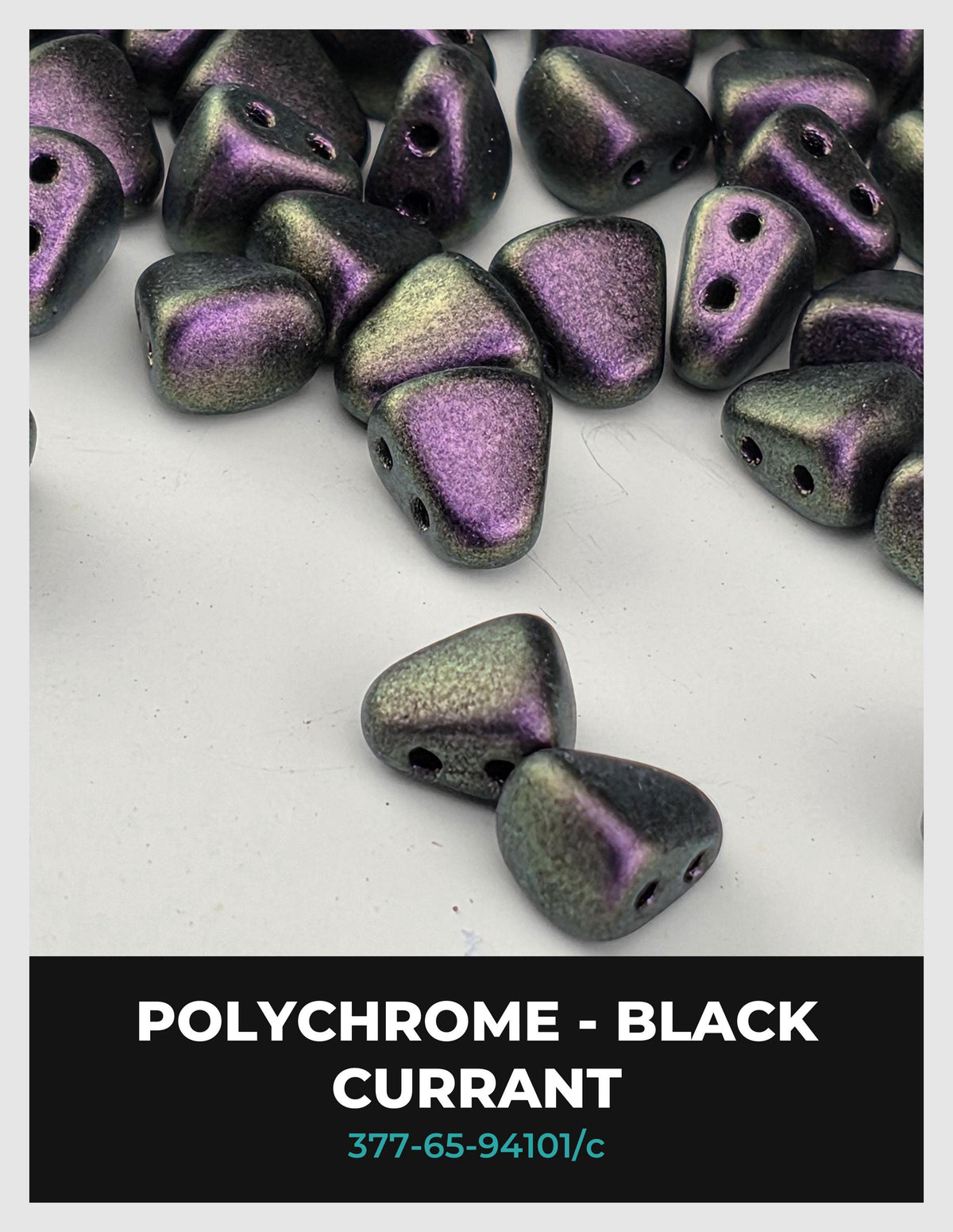 a collection of black, purple, and green polychrome beads scattered on a white background.